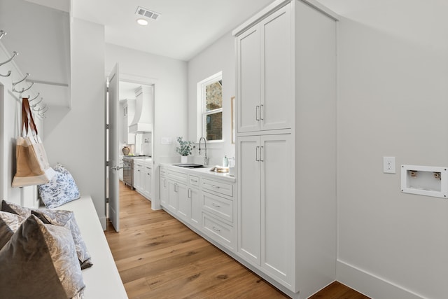 interior space featuring light wood-style flooring, a sink, visible vents, white cabinets, and light countertops