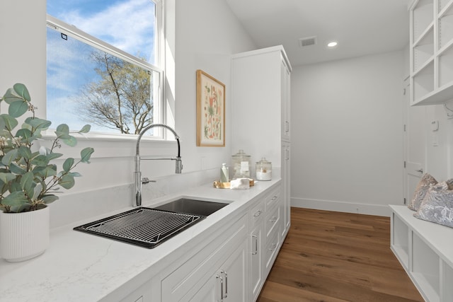 kitchen featuring dark wood finished floors, visible vents, white cabinets, and a sink