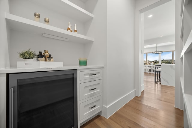 bar featuring wine cooler, recessed lighting, baseboards, light wood-style floors, and a dry bar