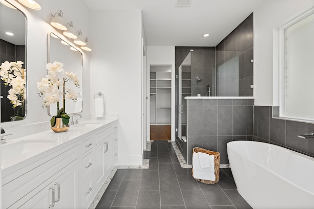 bathroom featuring a sink, a freestanding bath, a shower stall, tile patterned floors, and double vanity