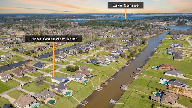 aerial view at dusk featuring a water view and a residential view