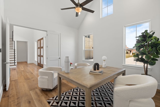 office space with ceiling fan, high vaulted ceiling, wood finished floors, and baseboards