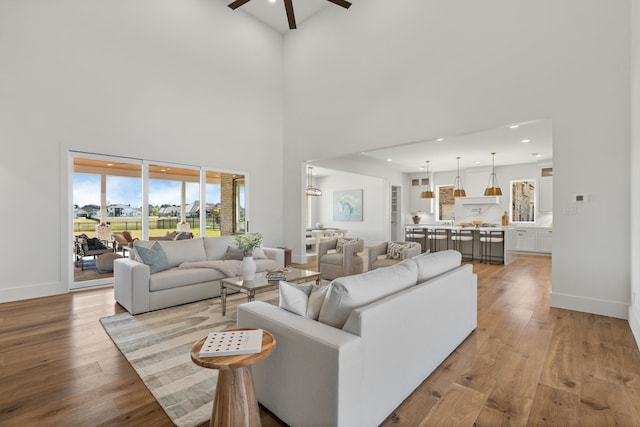 living area with a ceiling fan, recessed lighting, baseboards, and light wood finished floors