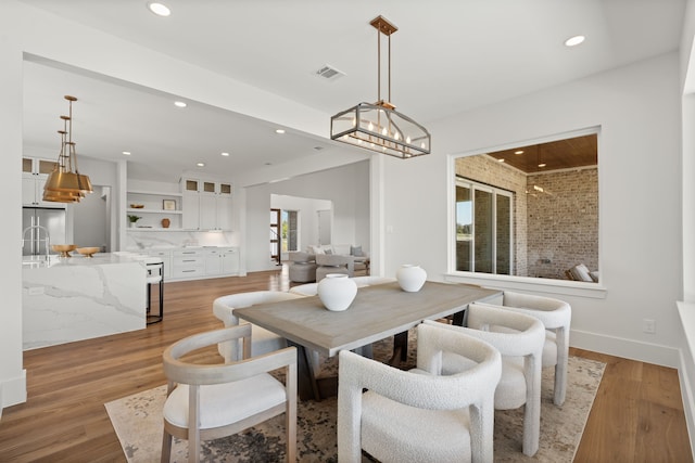 dining space featuring light wood finished floors, baseboards, an inviting chandelier, and recessed lighting