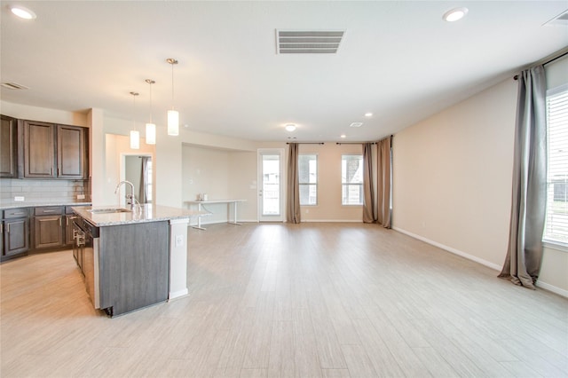 kitchen featuring pendant lighting, sink, light hardwood / wood-style flooring, light stone counters, and tasteful backsplash