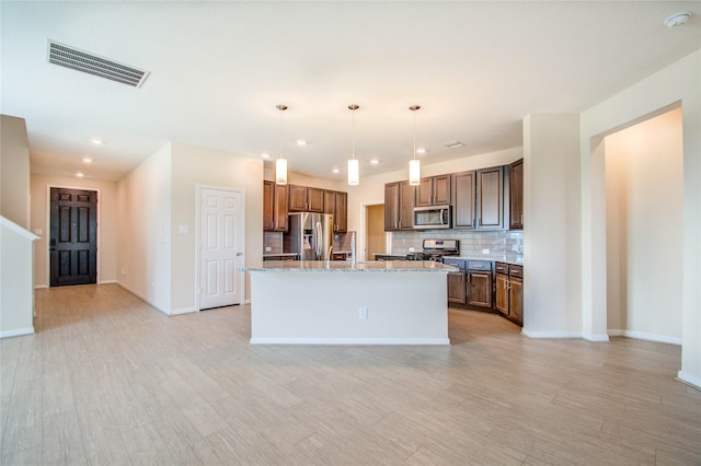 kitchen with appliances with stainless steel finishes, a kitchen island, pendant lighting, light stone countertops, and backsplash