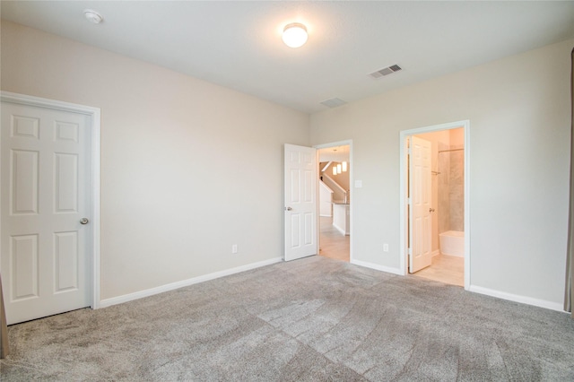 unfurnished bedroom featuring light colored carpet and ensuite bath