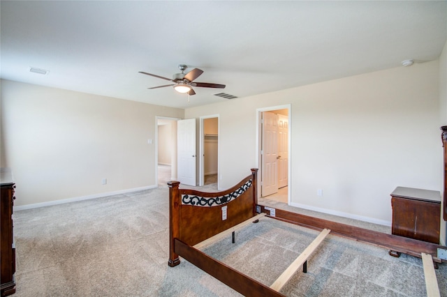 carpeted bedroom featuring a walk in closet and ceiling fan