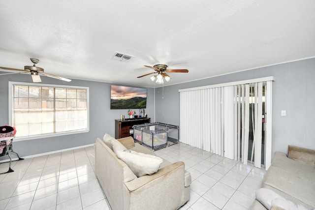 living room with a textured ceiling, ceiling fan, and light tile patterned flooring