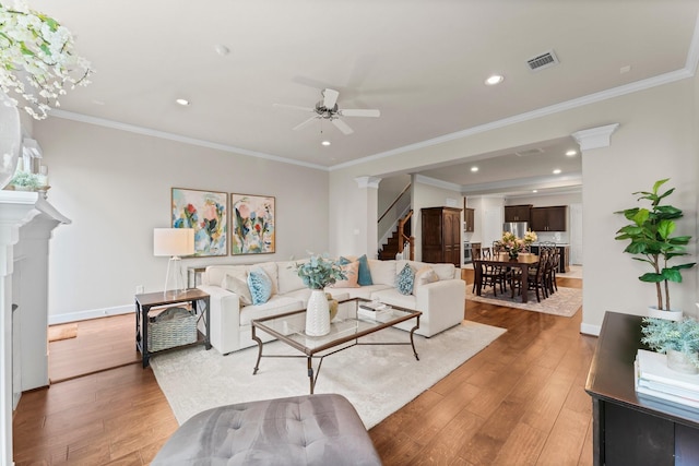 living room with hardwood / wood-style floors, crown molding, and ceiling fan