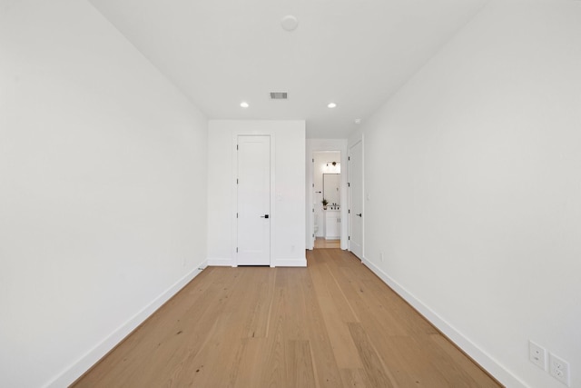 corridor with light wood-type flooring, baseboards, visible vents, and recessed lighting