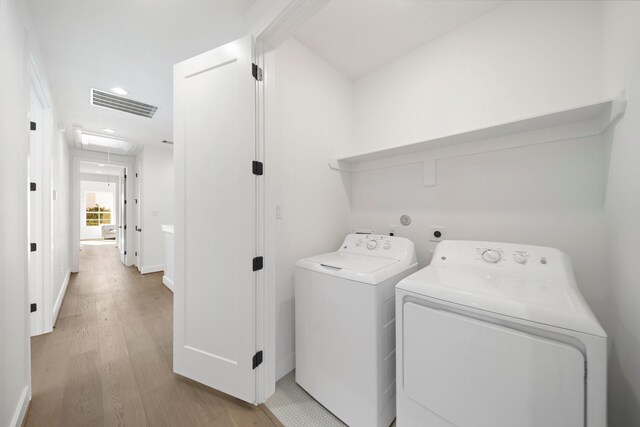 laundry room with light hardwood / wood-style floors and washing machine and dryer