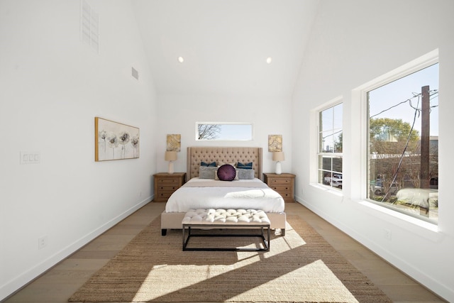 bedroom featuring light wood finished floors, visible vents, high vaulted ceiling, and baseboards