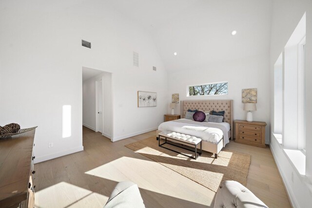 bedroom with high vaulted ceiling and light wood-type flooring