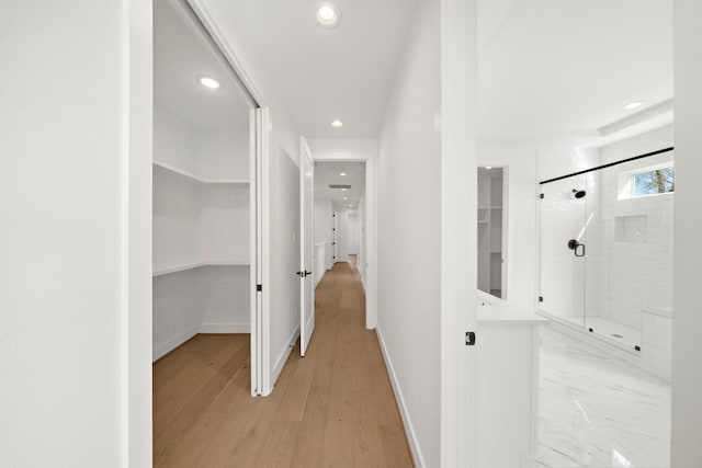 hallway featuring recessed lighting, light wood-style flooring, and baseboards