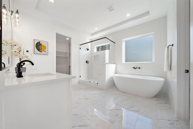 bathroom with independent shower and bath, vanity, tile walls, and a tray ceiling