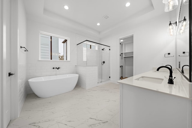 bathroom featuring vanity, separate shower and tub, tile walls, and a tray ceiling