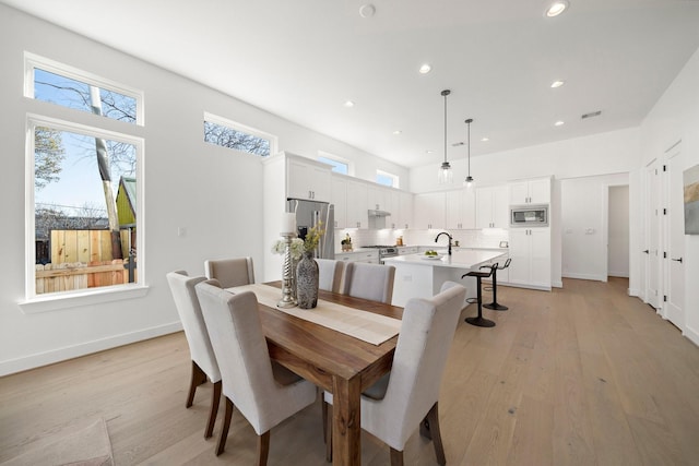 dining area featuring light hardwood / wood-style floors and a high ceiling