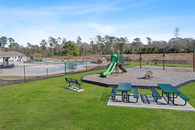 community jungle gym with a lawn, a community pool, and fence