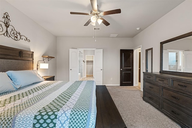 bedroom with a walk in closet, light colored carpet, visible vents, ceiling fan, and baseboards