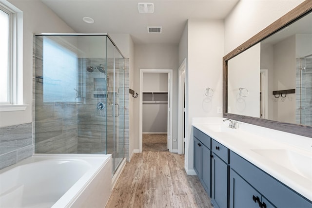 full bath with double vanity, visible vents, a spacious closet, a shower stall, and a sink