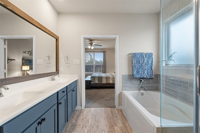 ensuite bathroom featuring double vanity, connected bathroom, a sink, and wood finished floors