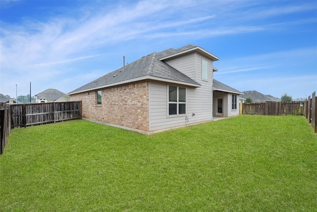 back of house featuring brick siding, a lawn, and a fenced backyard