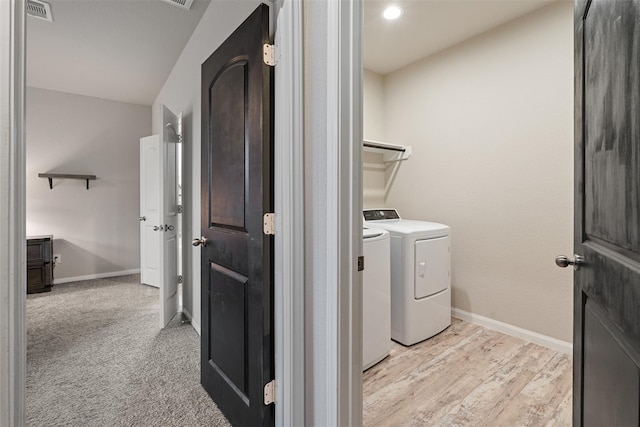 laundry area with baseboards, visible vents, laundry area, light wood-type flooring, and washer and clothes dryer