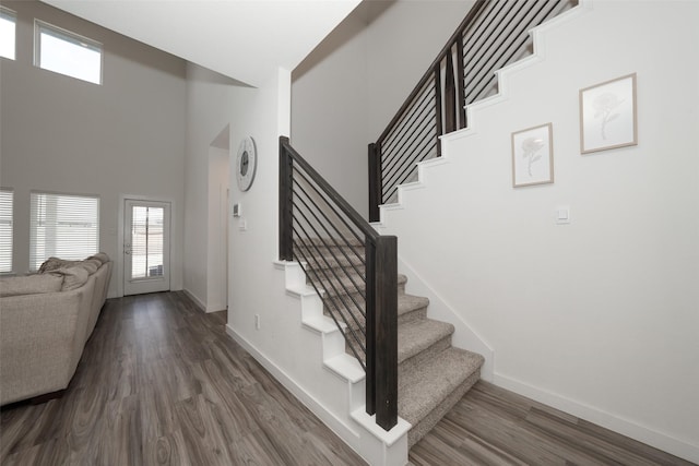 staircase with wood-type flooring and a high ceiling