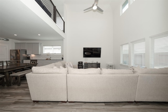 living room featuring hardwood / wood-style floors, ceiling fan, and a high ceiling