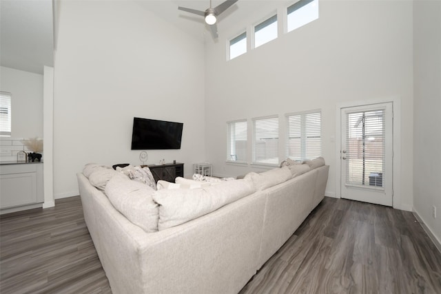 living room with dark hardwood / wood-style flooring, ceiling fan, and a high ceiling