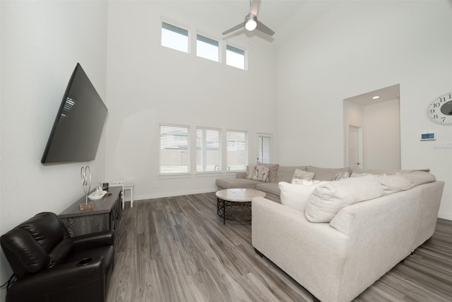 living room with a towering ceiling, hardwood / wood-style floors, and ceiling fan