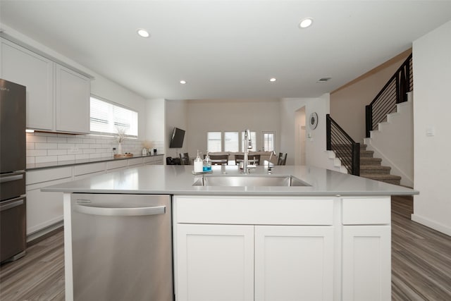 kitchen featuring sink, white cabinetry, stainless steel appliances, a center island with sink, and decorative backsplash