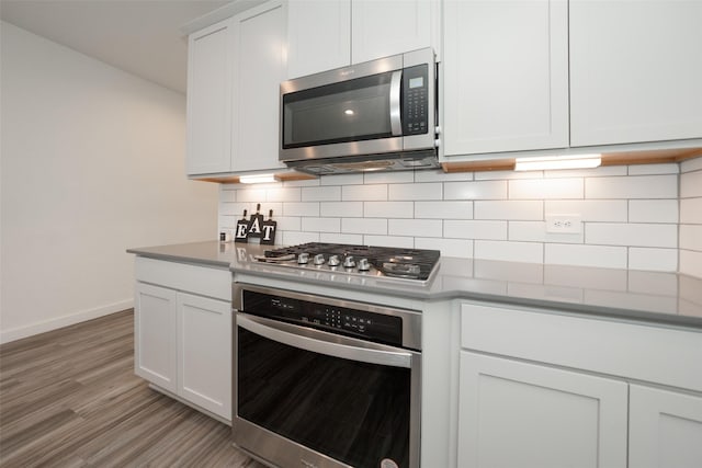 kitchen featuring stainless steel appliances, white cabinetry, light wood-type flooring, and decorative backsplash