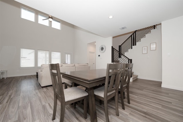 dining space with wood-type flooring and a high ceiling