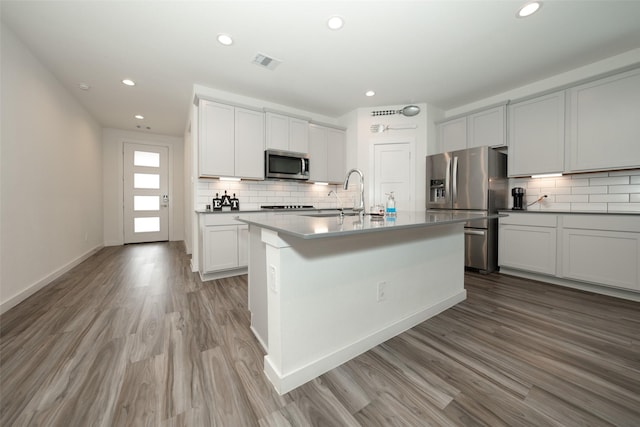 kitchen featuring sink, light wood-type flooring, appliances with stainless steel finishes, an island with sink, and white cabinets