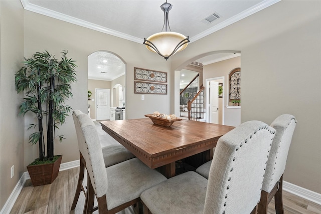 dining area with crown molding and light hardwood / wood-style floors