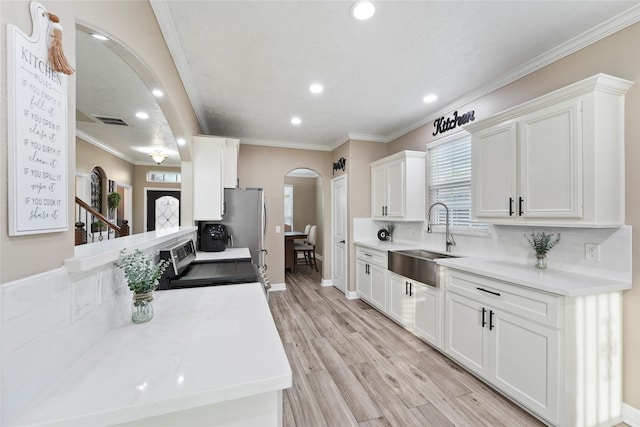 kitchen with white cabinetry, sink, range with electric cooktop, and light wood-type flooring