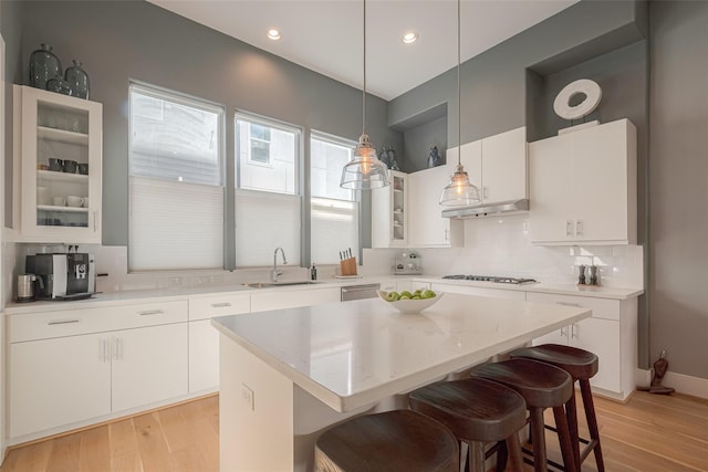 kitchen featuring sink, white cabinetry, a center island, gas cooktop, and pendant lighting