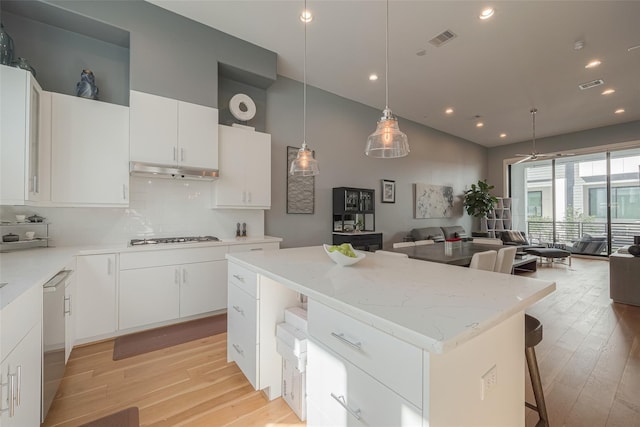 kitchen featuring light hardwood / wood-style flooring, a center island, gas stovetop, white cabinets, and decorative light fixtures