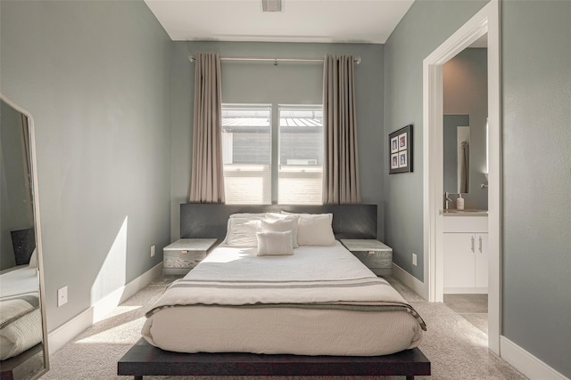 bedroom featuring light colored carpet and ensuite bath