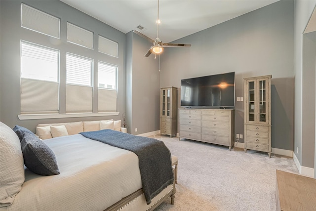 bedroom featuring a high ceiling, light colored carpet, and ceiling fan