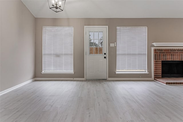 interior space featuring an inviting chandelier, a fireplace, and light hardwood / wood-style flooring