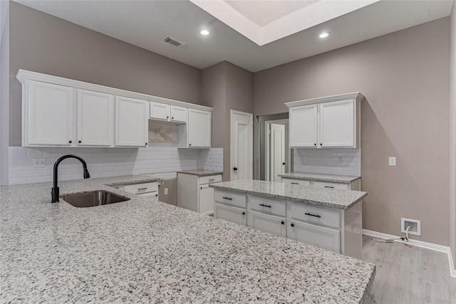 kitchen featuring white cabinetry, sink, and light stone counters