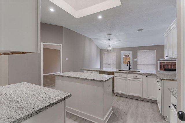 kitchen with sink, decorative light fixtures, a center island, kitchen peninsula, and white cabinets