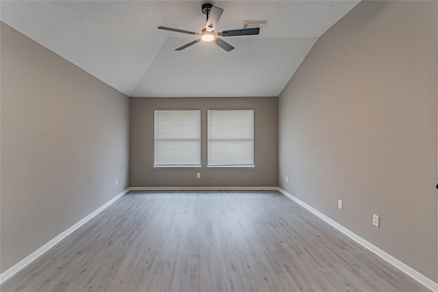 spare room with vaulted ceiling, ceiling fan, light hardwood / wood-style floors, and a textured ceiling