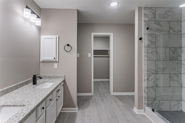 bathroom featuring vanity, hardwood / wood-style flooring, a textured ceiling, and tiled shower