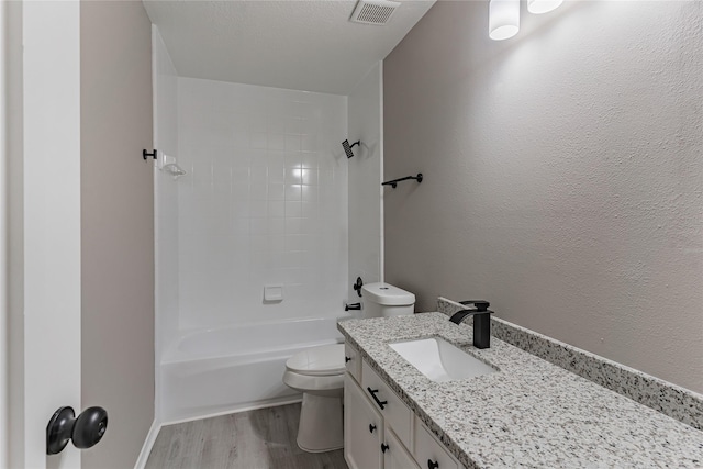 full bathroom featuring tiled shower / bath combo, vanity, wood-type flooring, a textured ceiling, and toilet