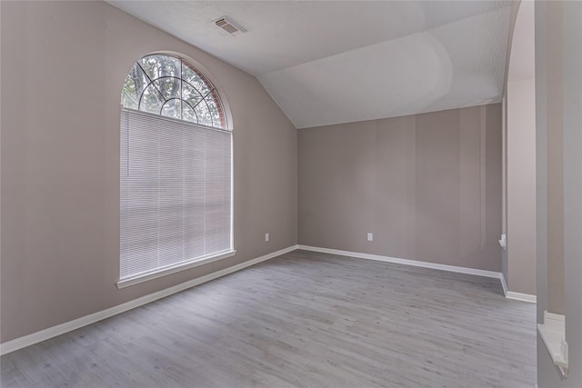 bonus room with lofted ceiling, light hardwood / wood-style flooring, and a textured ceiling