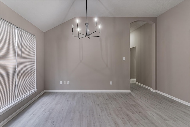 unfurnished dining area featuring vaulted ceiling, an inviting chandelier, and light wood-type flooring